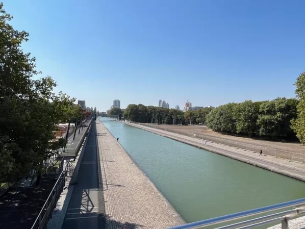 A river with a bridge, trees, and buildings in the background.