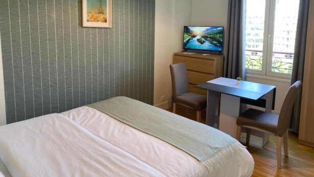 A hotel room with a bed, a desk with a chair, a television, and a window with curtains. - Studio number 7 in Pantin (Pantin)