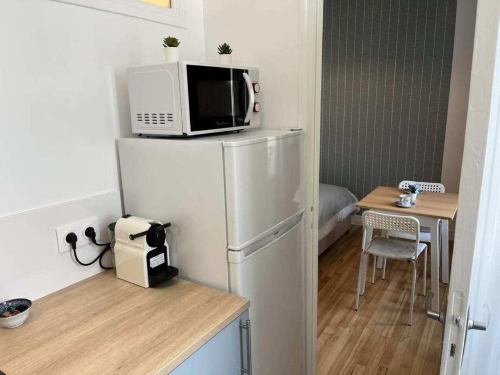 A compact kitchenette with a microwave, coffee machine, and a small table with a chair. - Studio number 7 in Pantin (Pantin)