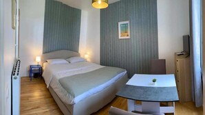 A hotel room with a bed, bedside table, lamp, and a small table with a chair. - Studio number 7 in Pantin (Pantin)