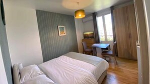 A bedroom with a bed, a desk, and a chair. There is a window with curtains, a picture on the wall, and a ceiling light. - Studio number 7 in Pantin (Pantin)