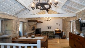 Un intérieur rustique avec un mur en pierre, des meubles en bois et un plafond haut avec des poutres apparentes.