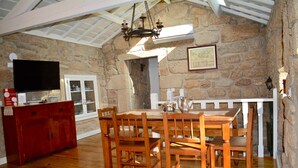 Un coin repas avec un mur en pierre, une table en bois et des chaises.