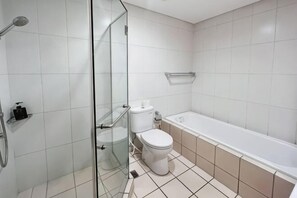 A bathroom with a glass shower enclosure, a toilet, and a bathtub.