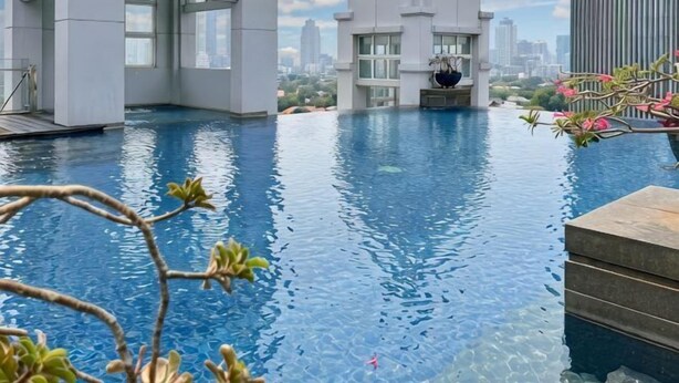 Une piscine à débordement dotée d’une architecture moderne et offrant une vue sur le paysage urbain.
