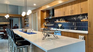 Una cucina moderna con isola in marmo, mobili in legno e zoccolo nero.