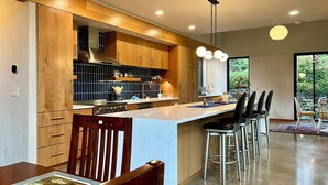 Una cucina moderna con mobili in legno, un'isola centrale con sgabelli da bar e illuminazione a sospensione.