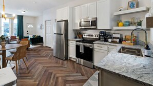 A modern kitchen with white cabinets, stainless steel appliances, and a herringbone wood floor. - 2615 Jane Down - Southside (Pittsburgh)
