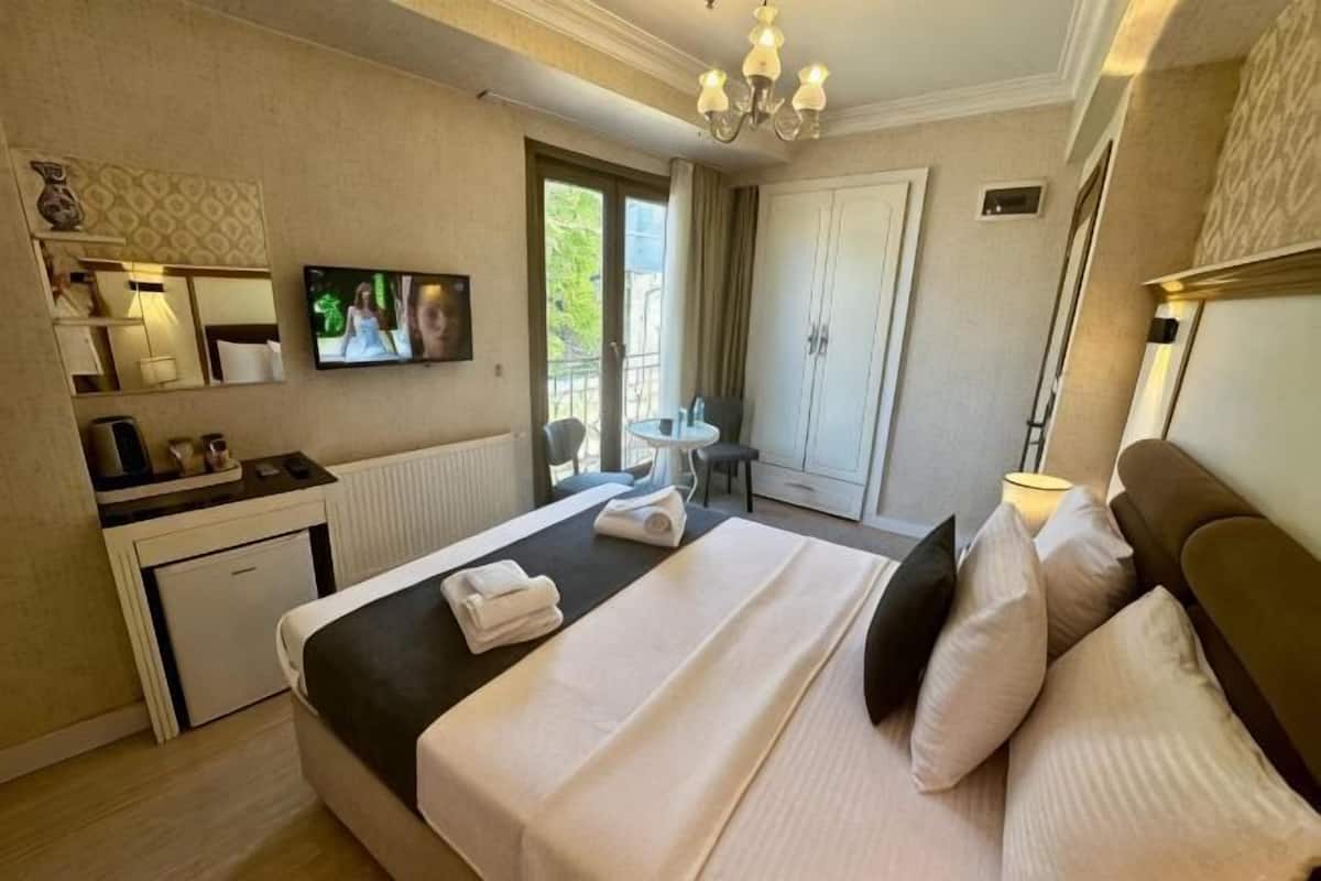 A hotel room with a bed, a desk, a chair, a TV, and a view of the outdoors.