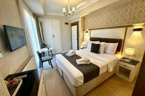 Una habitación de hotel con cama, mesita de noche, escritorio, silla y televisor.