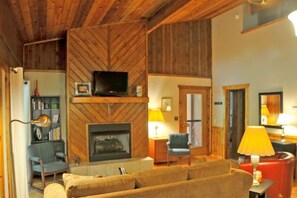 A cozy living room with a fireplace, a television, and a sofa.