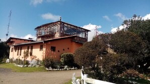 Un edificio de dos pisos con un balcón de madera y una chimenea.