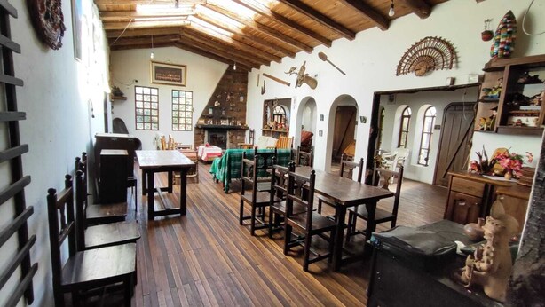 Un interior rústico con vigas de madera, una chimenea y un comedor con bancos y mesas.