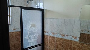 Un baño con inodoro, lavamanos y zona de ducha.