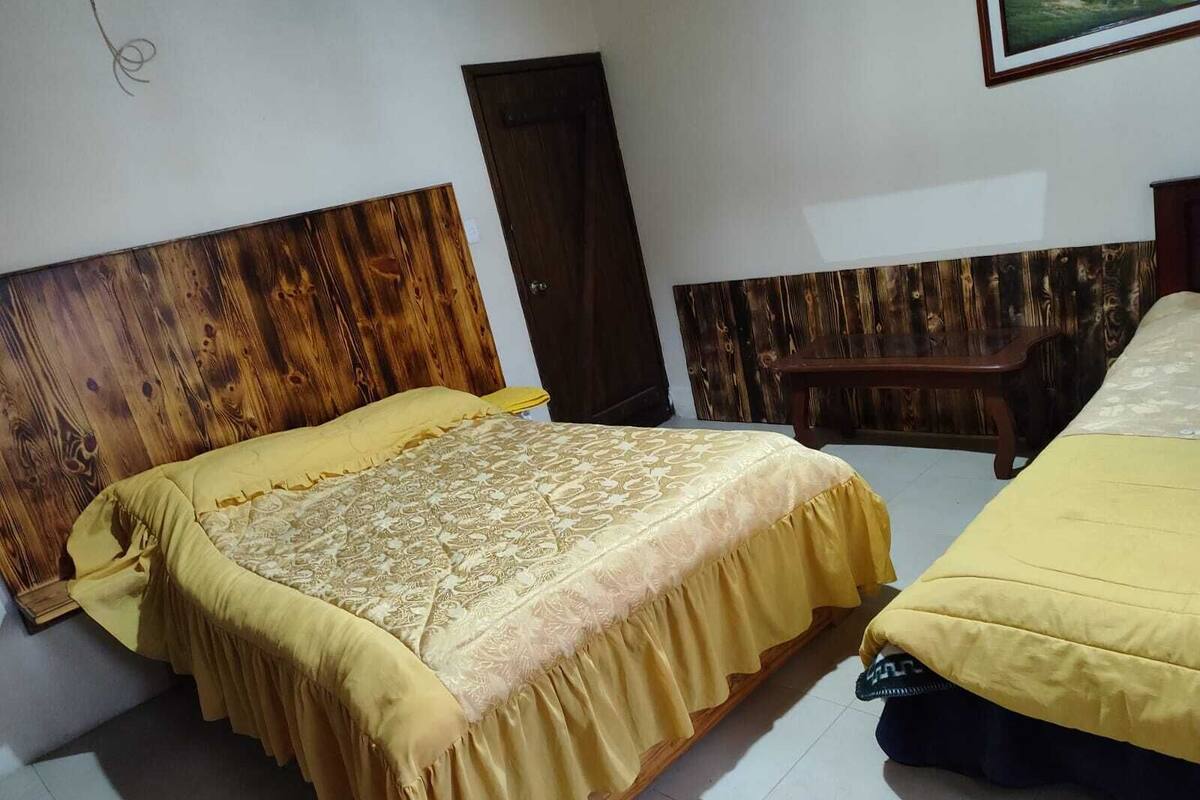 Een slaapkamer met twee bedden, houten hoofdborden en een klein houten tafeltje.