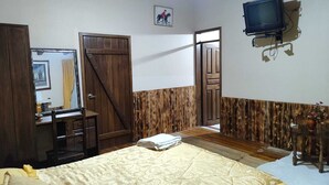 Un dormitorio con cama, cómoda, televisión y puerta que da a otra habitación.