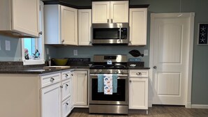 A kitchen with white cabinets, a stainless steel oven, and a microwave.