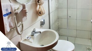 A bathroom with a sink, toilet, and a shower area. - Hotel Benfica (Aparecida)
