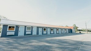 A row of motel rooms with individual doorways, a central air conditioning unit, and a parking lot. - The Pendergrass Room, Lakeside Inn at Dale Hollow (Monroe)