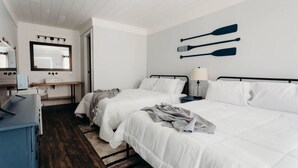 Habitación de hotel con dos camas, un escritorio, un espejo y una decoración de tabla de remo fijada a la pared.