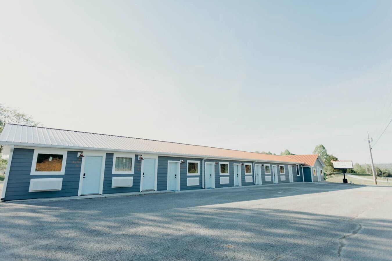 Fila de habitaciones de motel con entradas individuales, unidad de aire acondicionado central y estacionamiento.