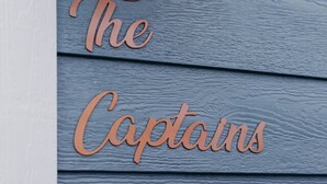Pared de madera con el texto "The Captains Care" en una fuente cursiva.