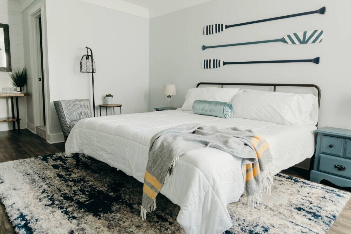 Quarto com cama, mesas de cabeceira, luminária e prateleira na parede com objetos.