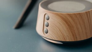 Un altavoz de madera con tres botones sobre una superficie azul.