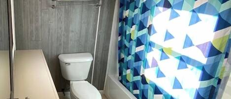 A modern bathroom with a toilet, a sink, and a shower curtain with a geometric pattern.
