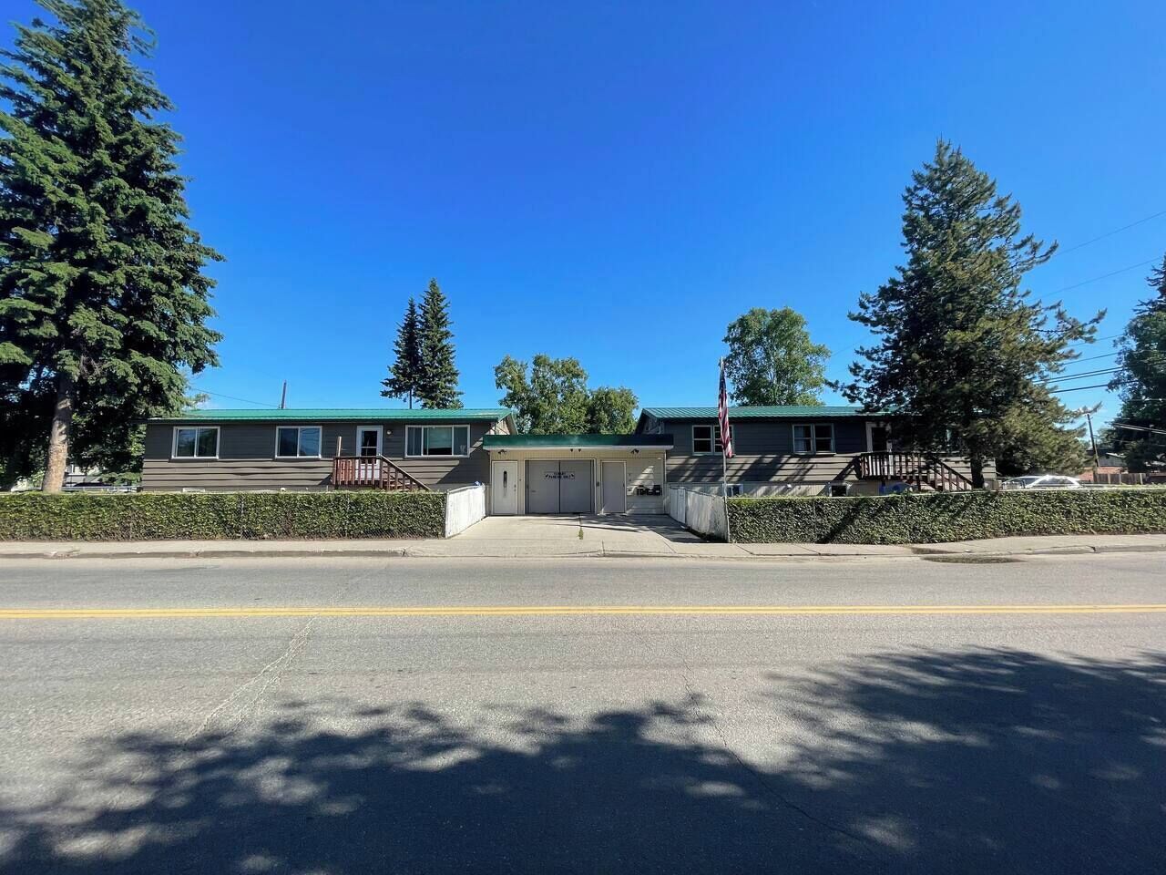 A two-story building with a green roof and a parking lot in front.