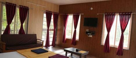 Una habitación con cama, sofá, mesa y cortinas.