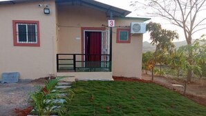 A building with a red door, a number 3 sign, and a small porch with a railing. - Bimal Farm Home Stay (Koroli)
