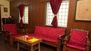 A room with a wooden sofa set, a wooden coffee table, and a red patterned cushion. - Bimal Farm Home Stay (Koroli)