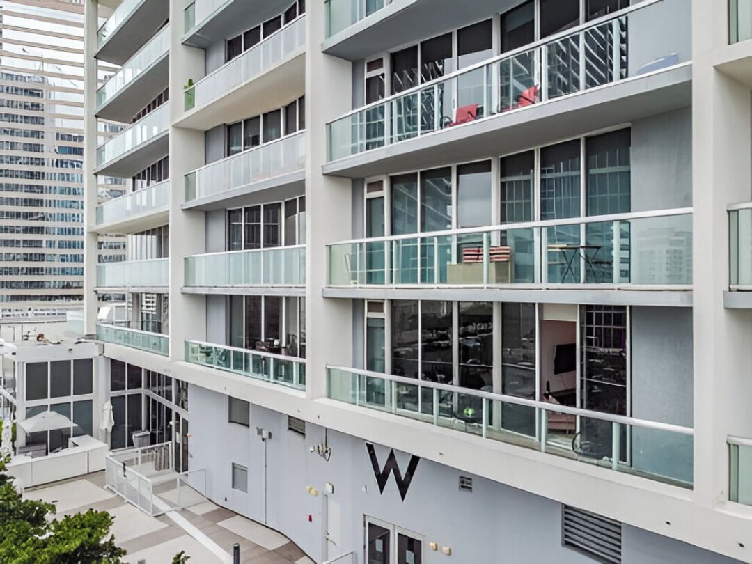 A multi-story building with balconies, large windows, and a prominent 'W' logo on the facade.