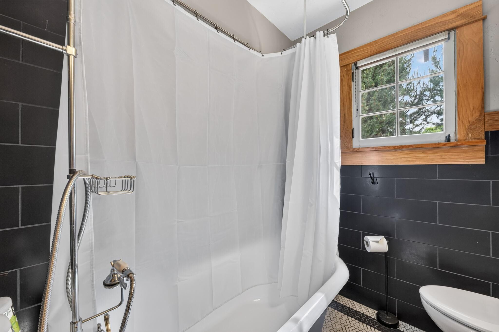 Une salle de bain avec douche, toilettes et fenêtre.