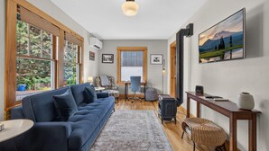 A cozy living room with a blue sofa, a wooden coffee table, a rug, and a fireplace. - Oak Millhouse - Beautifully restored home in Downtown Old Bend (Bend)