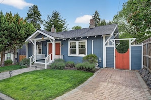 A single-story house with a front porch, a brick pathway, and a wooden fence.