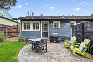 A house with a patio, a grill, and outdoor seating.