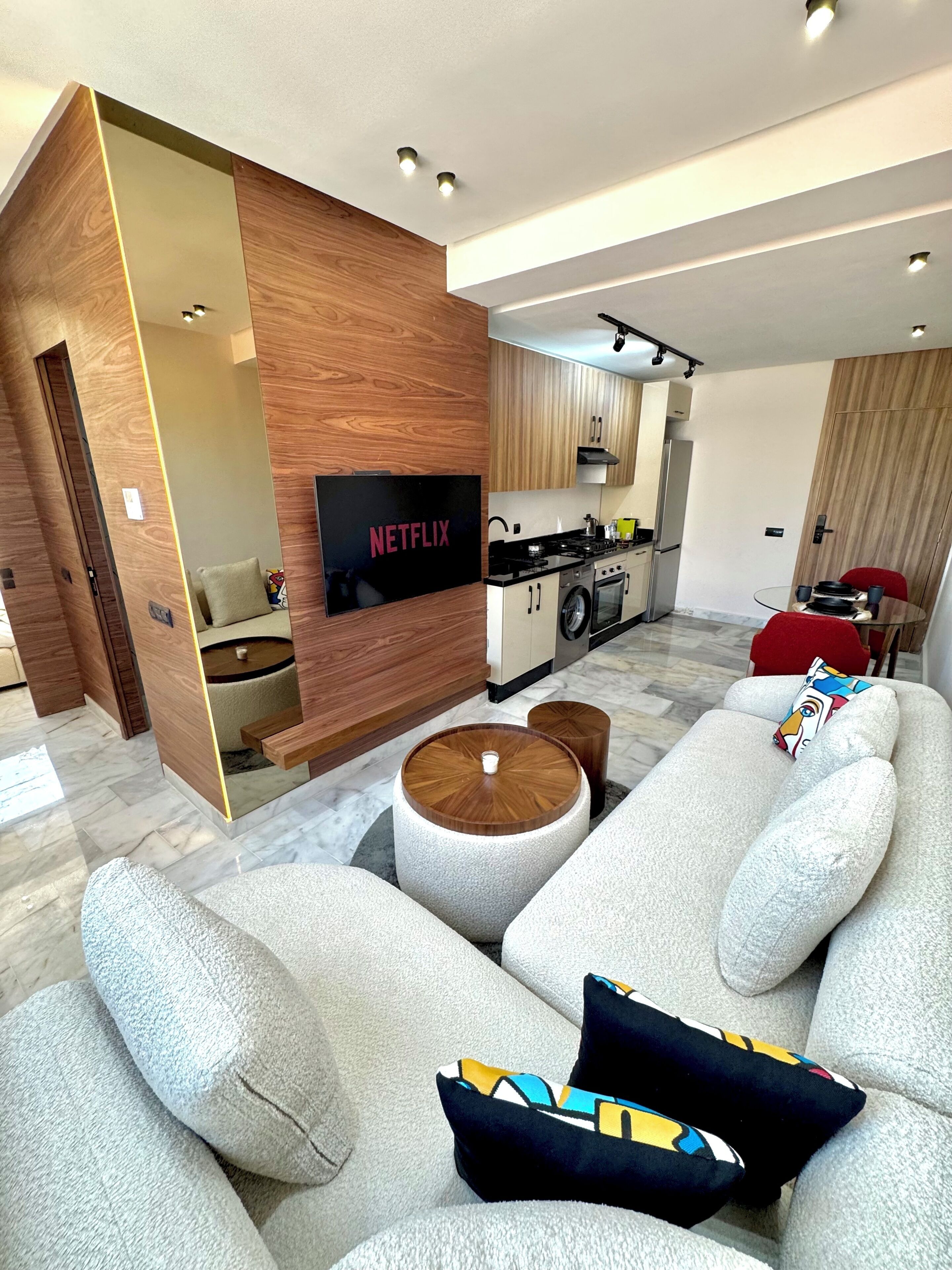 A modern living room with a grey sofa, a coffee table, and a kitchen in the background.