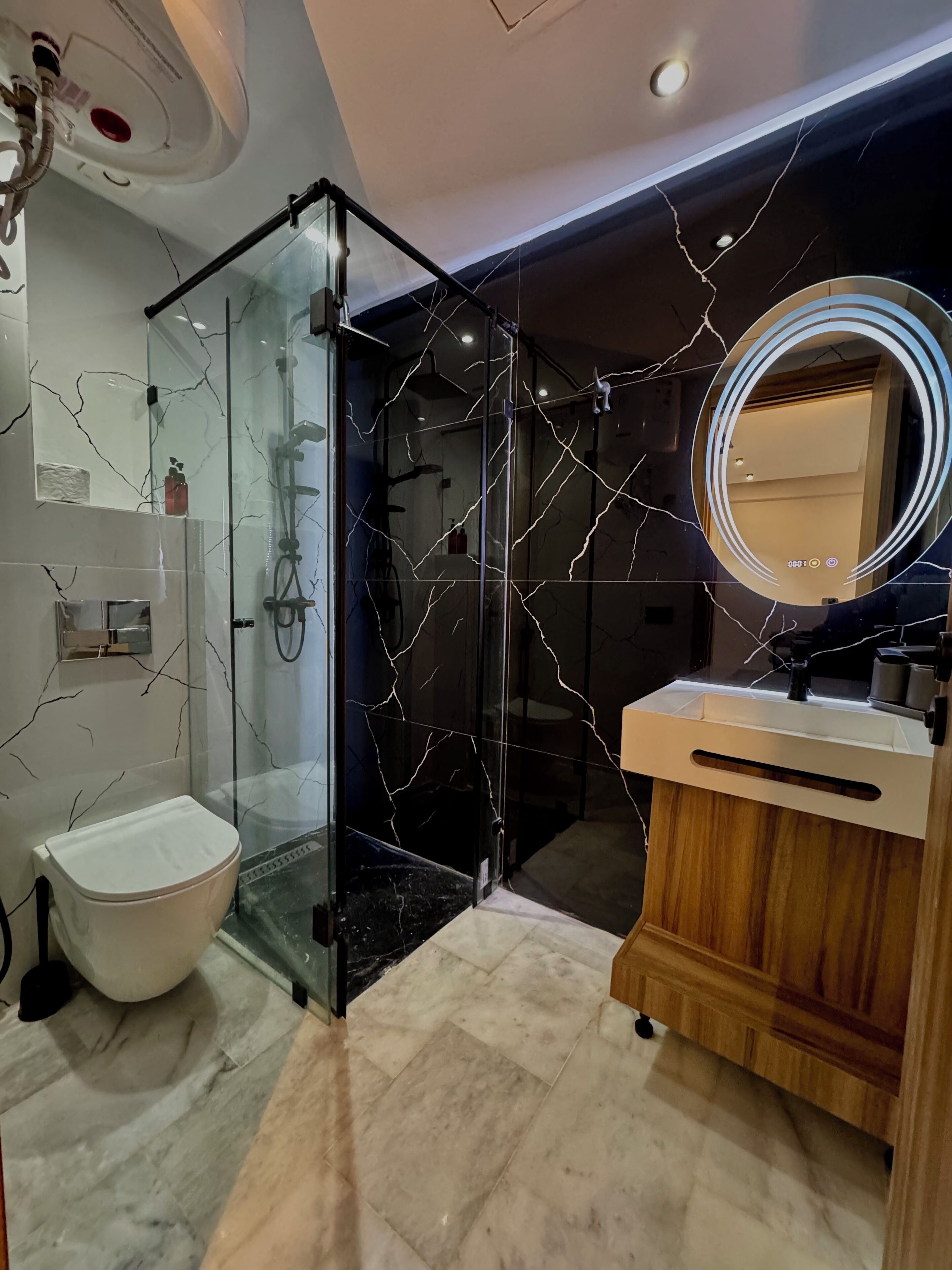 A modern bathroom with a glass-enclosed shower, a white toilet, and a vanity with a wooden cabinet.