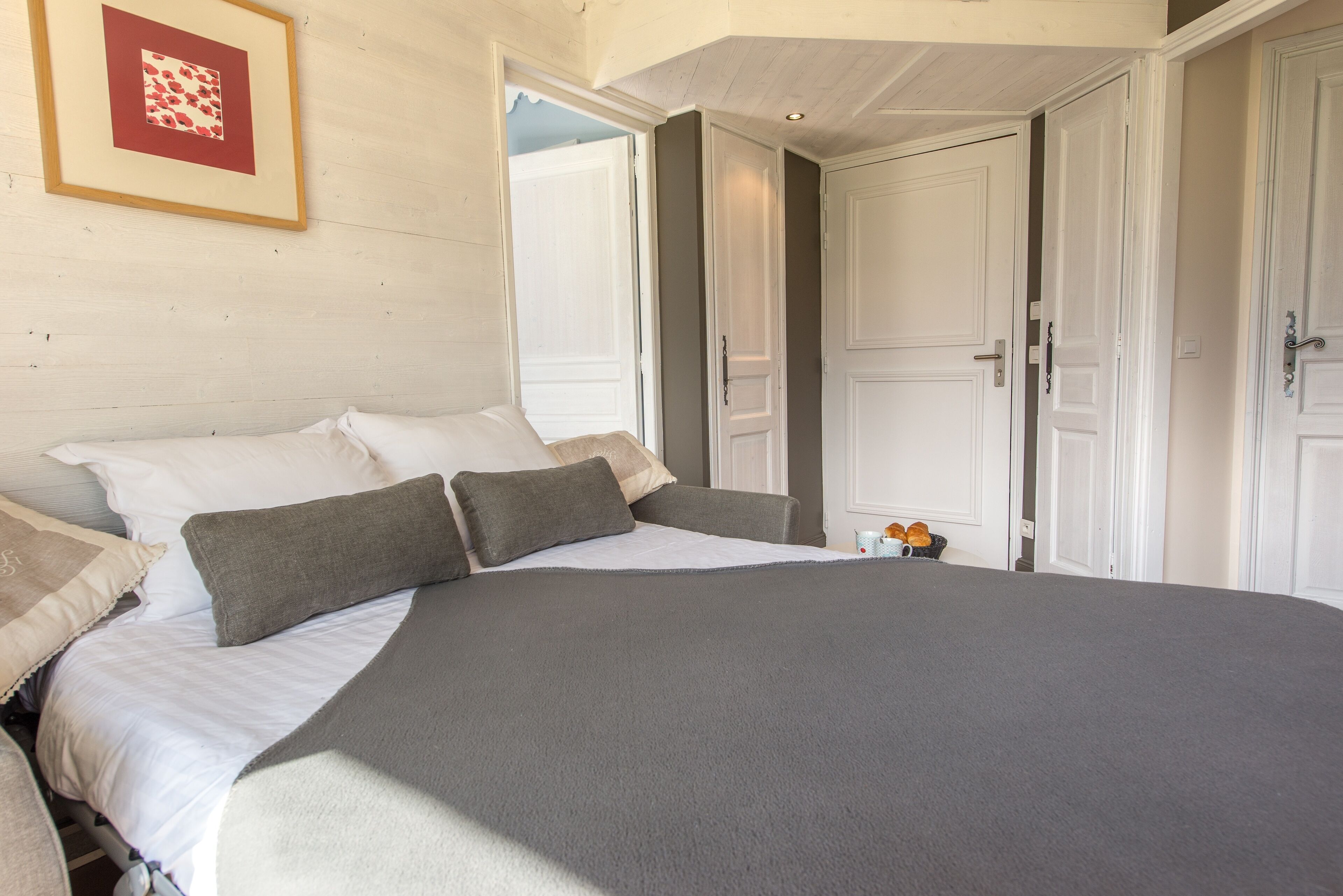Une chambre à coucher avec un grand lit, des murs blancs et un tableau encadré accroché au mur.