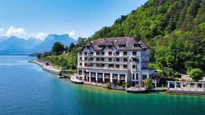 A multi-story hotel with balconies, situated by a lake with mountains in the background. - Le Spacieux Rivage - Appartement d’exception, pieds dans l’eau (Duingt)