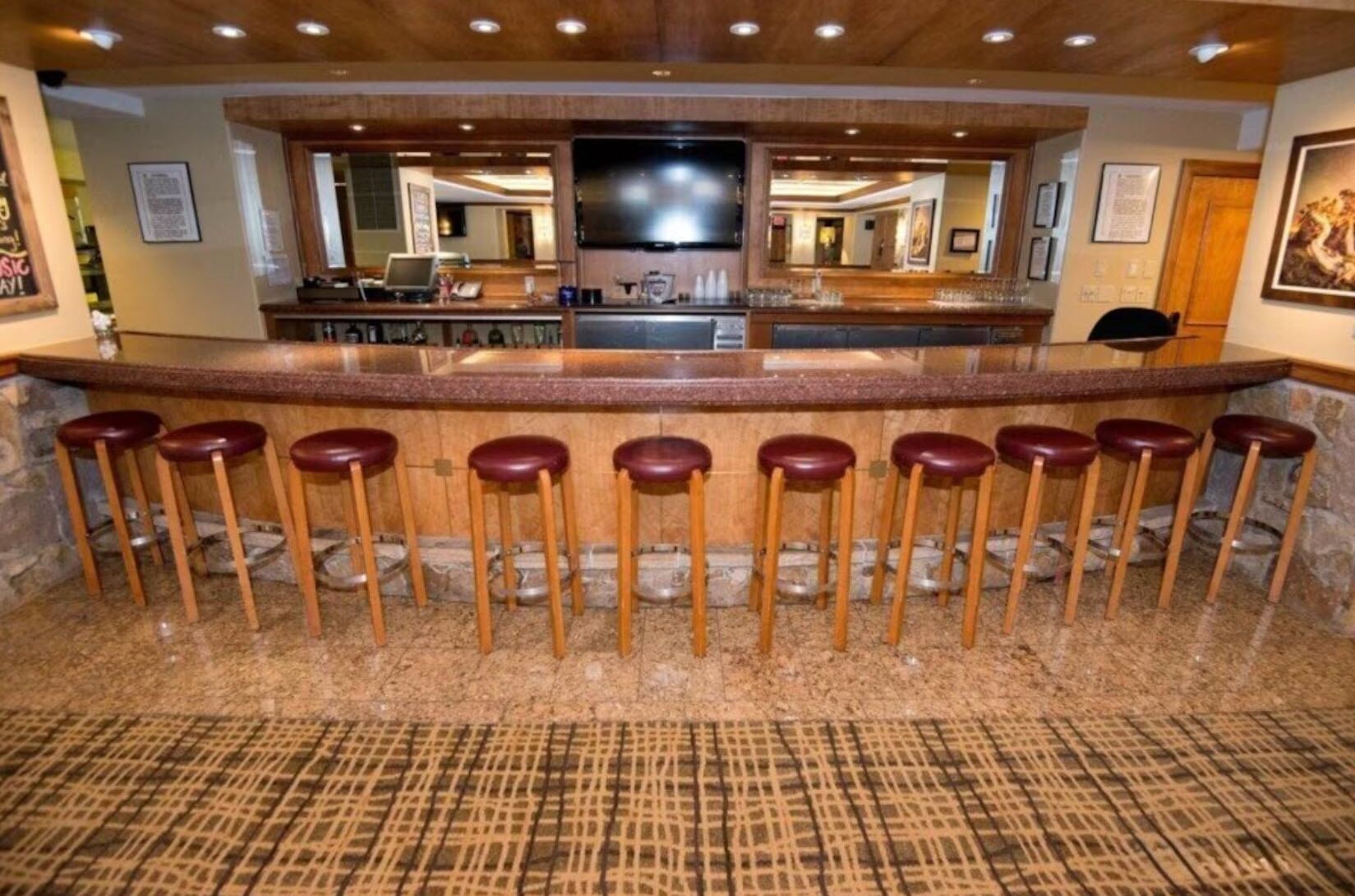 A bar area with a counter, stools, and a television screen.