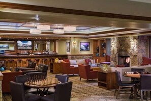 A spacious lounge area with a bar, comfortable seating, a fireplace, and a large screen TV. - Studio Plus Hilton Valdoro Mountain Lodge Luxury Ski Resort 11/07/25 - 11/13/25 (Breckenridge)