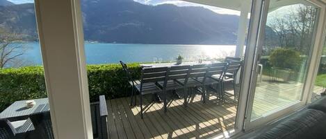 Une terrasse dotée de mobilier d’extérieur, offrant une vue sur un lac et des montagnes.