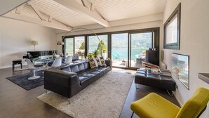 A modern living room with a black leather sofa, a yellow armchair, and a glass dining table.