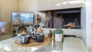 Una sala de estar moderna con una mesa de centro de vidrio, una chimenea, un televisor y un rincón de estar acogedor.
