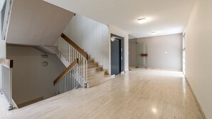 A spacious, well-lit hallway with a wooden staircase and a door leading to another room.