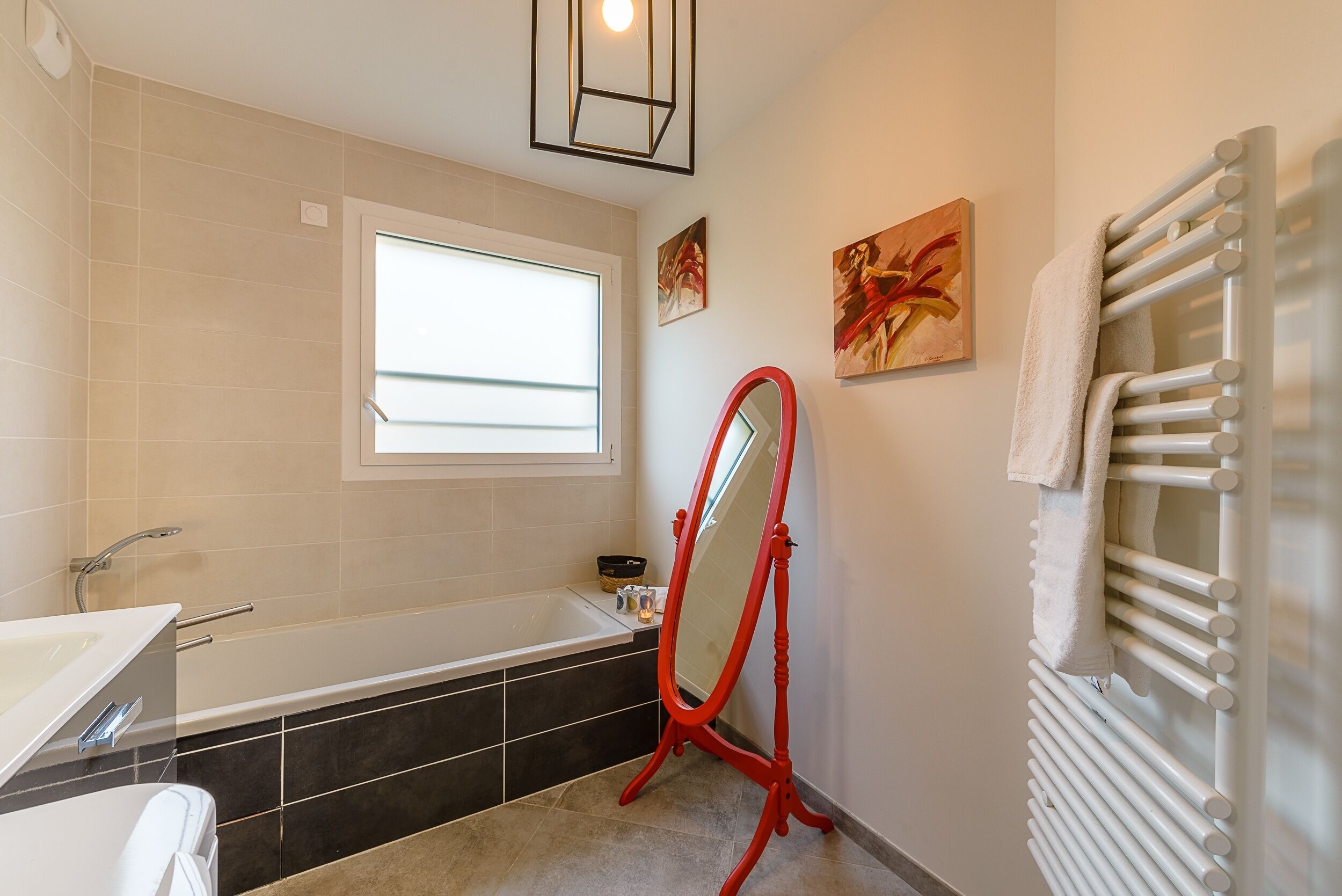 A modern bathroom with a bathtub, a large mirror, and a towel rack.