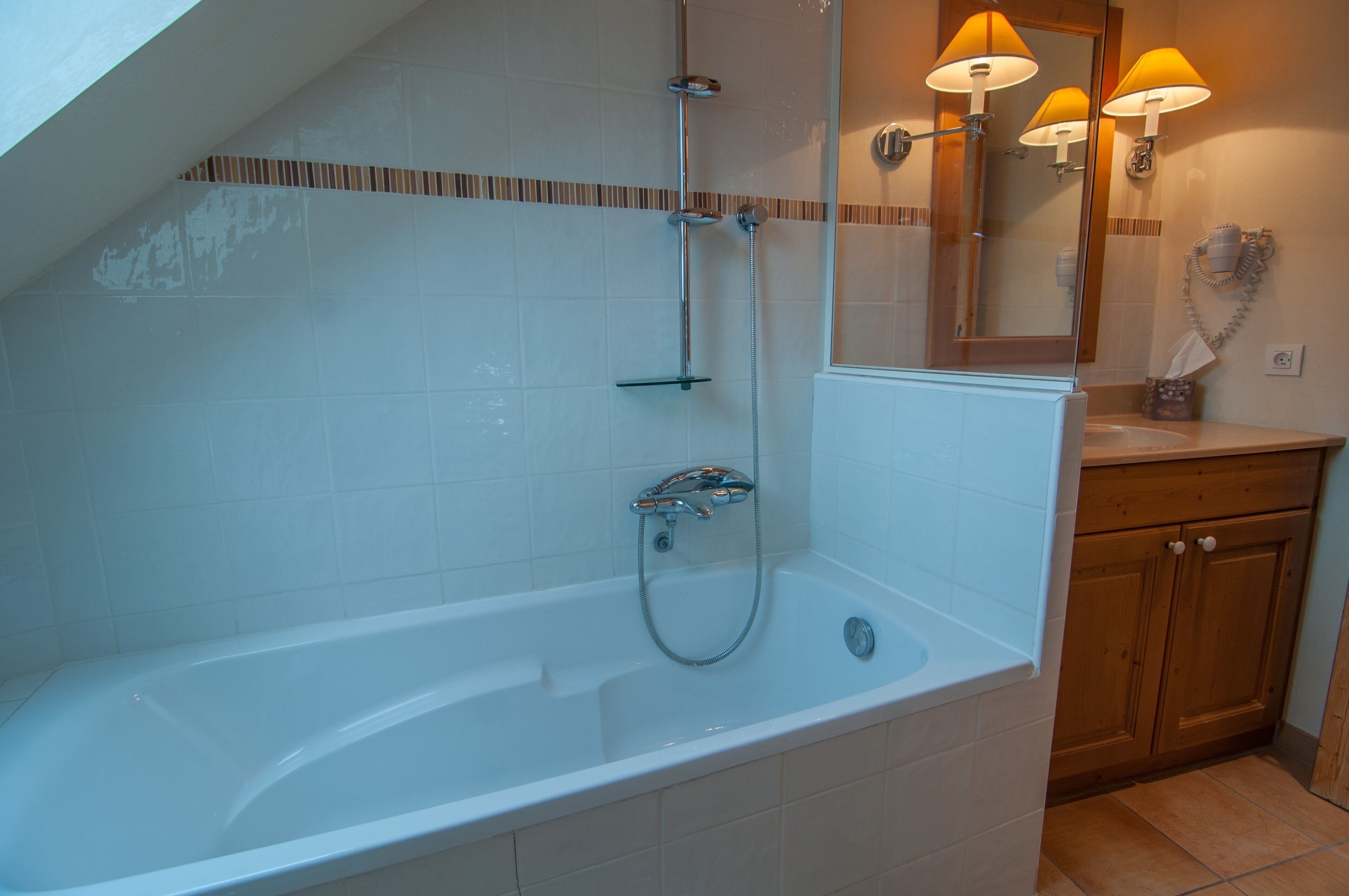 Een moderne badkamer met een vrijstaand bad, een douchekop en een wastafel met spiegel en handdoekhouder.